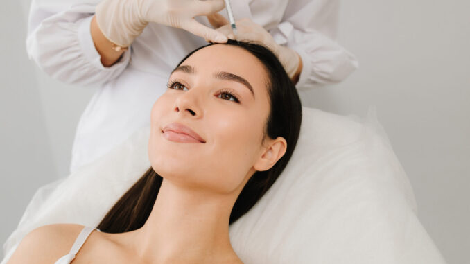 PRP Behandlung der Haare bei einer Frau: Ärztliches Fachpersonal injiziert plättchenreiches Plasma in die Kopfhaut